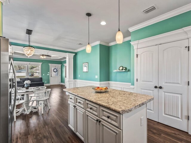 kitchen with decorative columns, light countertops, visible vents, freestanding refrigerator, and open floor plan