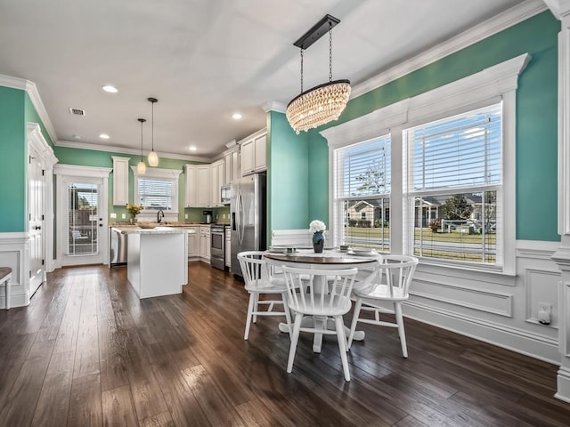 dining space with ornamental molding, a healthy amount of sunlight, dark wood finished floors, and a decorative wall