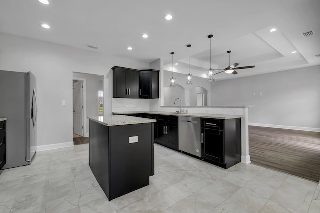 kitchen featuring kitchen peninsula, a center island, stainless steel appliances, and hanging light fixtures