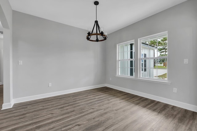 empty room with dark hardwood / wood-style flooring and a notable chandelier