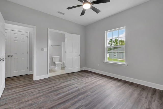 unfurnished bedroom with ceiling fan, a closet, dark wood-type flooring, and ensuite bath