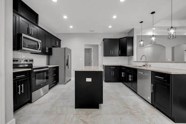 kitchen featuring tasteful backsplash, stainless steel appliances, sink, decorative light fixtures, and a center island