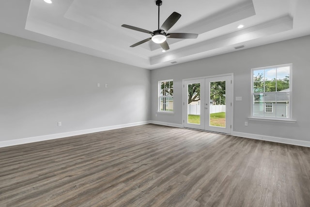 unfurnished room featuring a raised ceiling, dark hardwood / wood-style flooring, and a healthy amount of sunlight