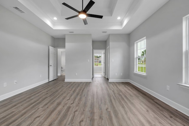 unfurnished living room featuring a raised ceiling, ceiling fan, and hardwood / wood-style floors