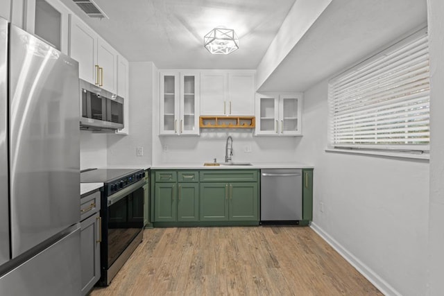 3142 Seattle Slew Ct, Tallahassee, FL 32309 - kitchen with appliances with stainless steel finishes, green cabinetry, a sink, white cabinets, and light wood-style flooring
