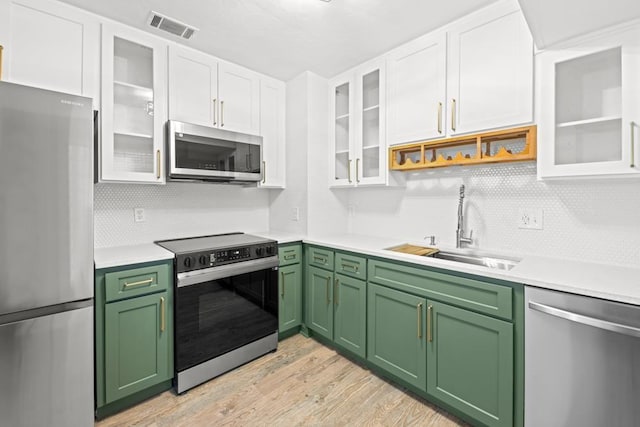3142 Seattle Slew Ct, Tallahassee, FL 32309 - kitchen with stainless steel appliances, green cabinets, a sink, white cabinetry, and backsplash