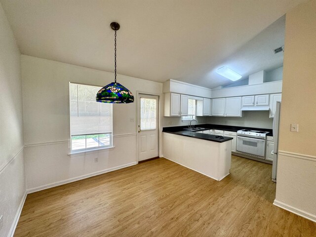 27 Pirates Cove Ln, Saint Marks, FL 32355 - kitchen with white appliances, a peninsula, light wood-style floors, white cabinets, and vaulted ceiling