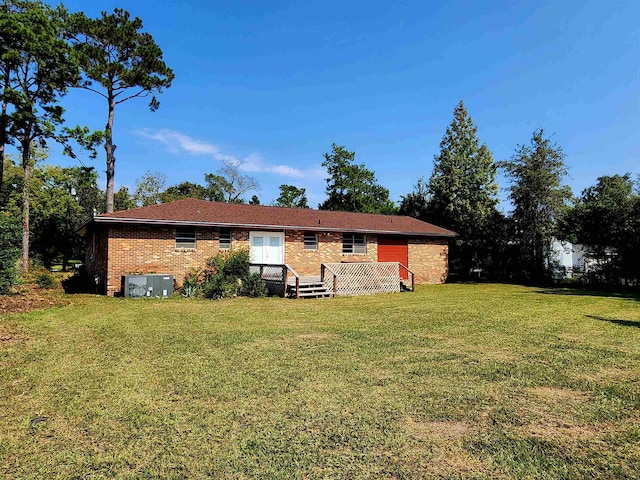 rear view of house featuring central AC unit and a lawn