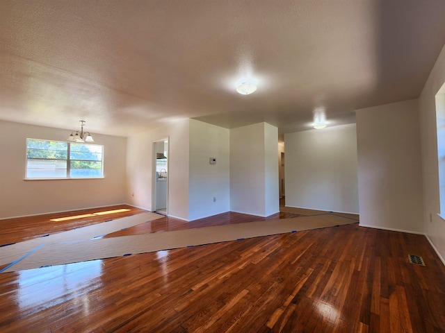 spare room with a textured ceiling, hardwood / wood-style flooring, and a chandelier