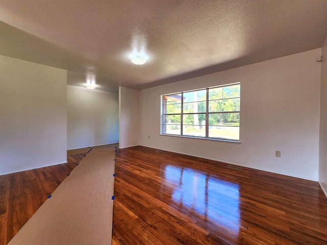 empty room featuring dark wood-type flooring and a textured ceiling