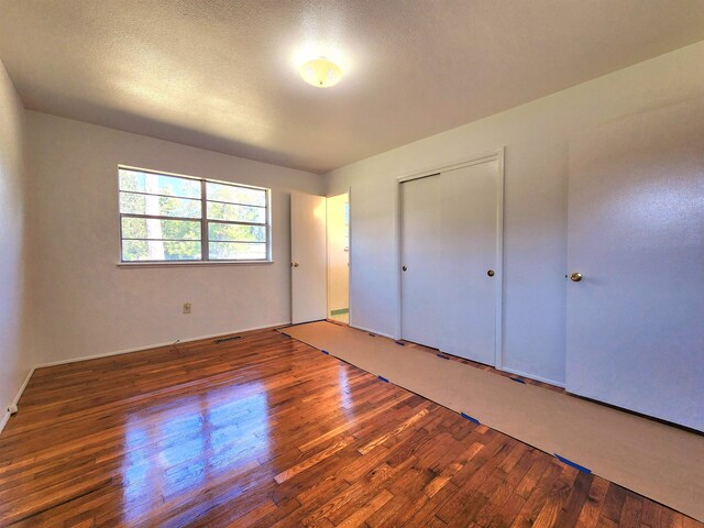 unfurnished bedroom with a textured ceiling, dark hardwood / wood-style floors, and a closet