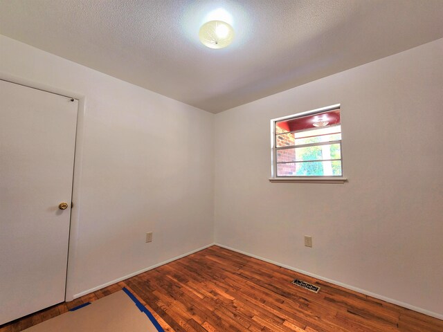 unfurnished room with hardwood / wood-style flooring and a textured ceiling