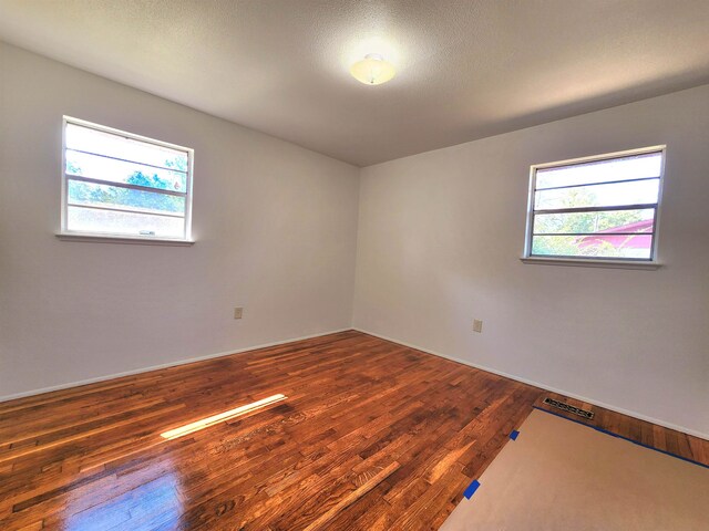 spare room featuring dark hardwood / wood-style floors and a textured ceiling