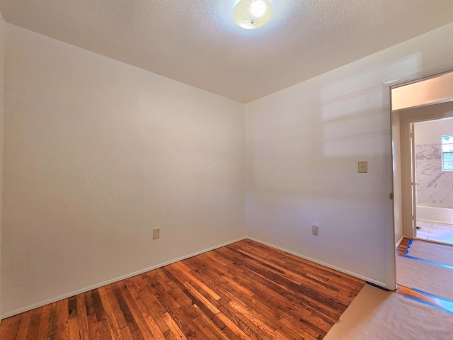 unfurnished room with wood-type flooring and a textured ceiling