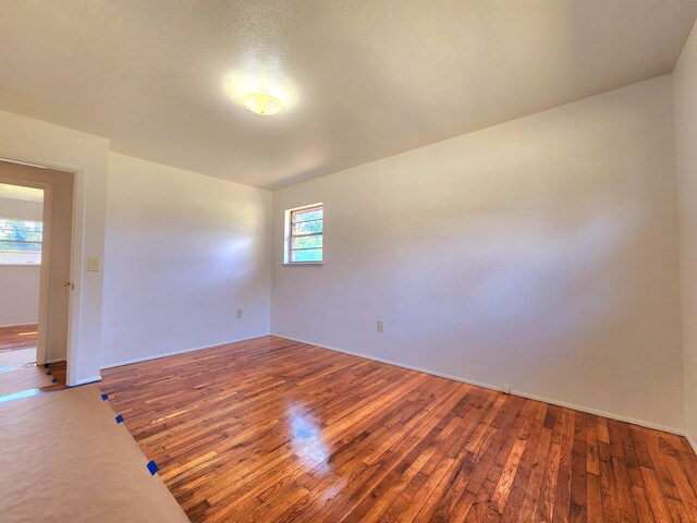 spare room with dark hardwood / wood-style floors and a textured ceiling