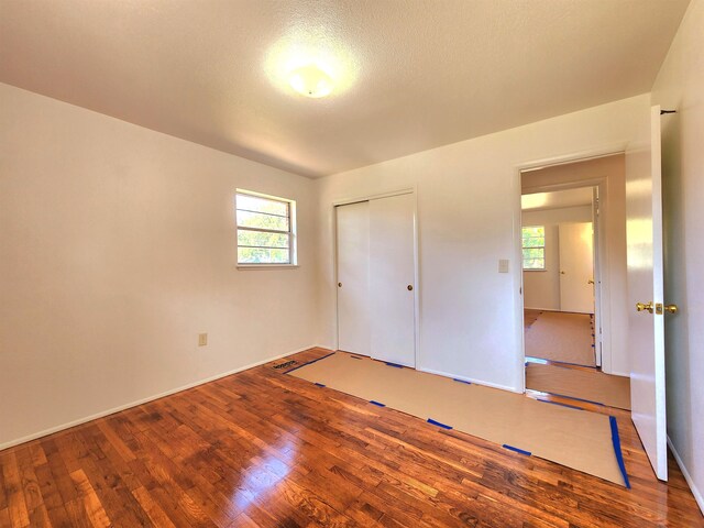 unfurnished bedroom with hardwood / wood-style floors, a textured ceiling, and a closet