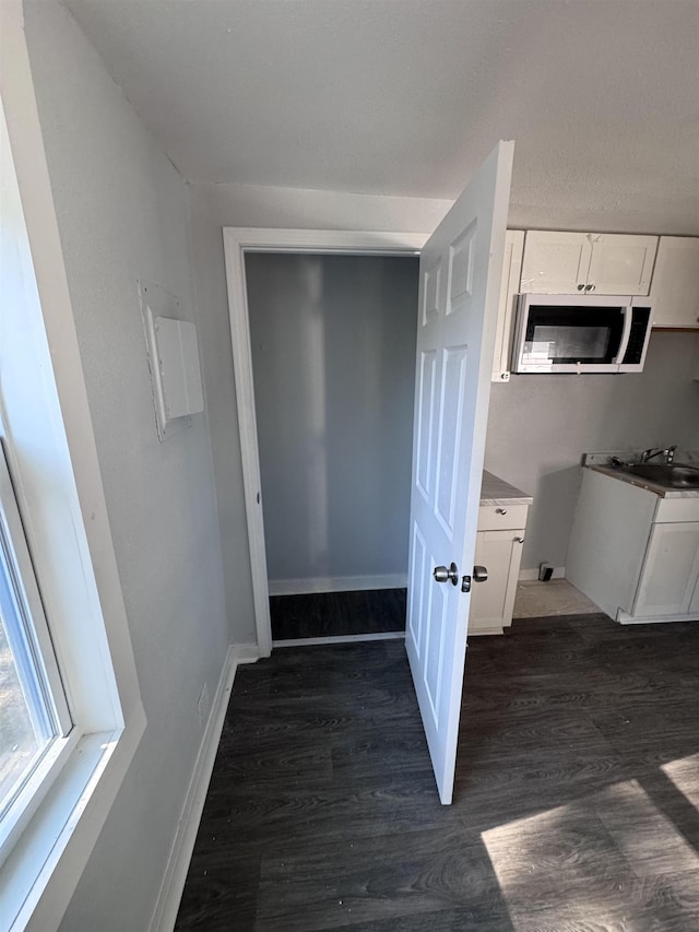 interior space featuring sink, dark wood-type flooring, and white cabinets