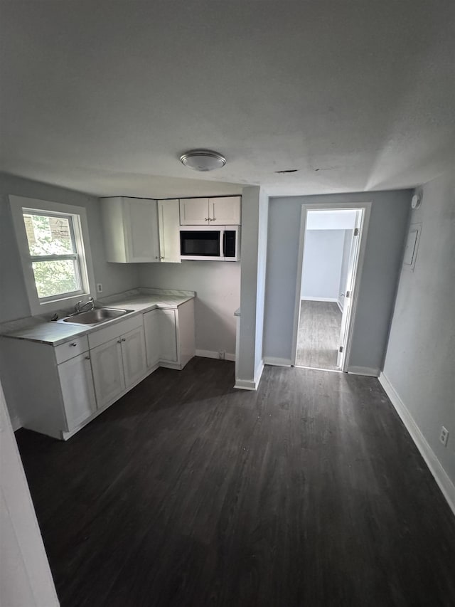 kitchen featuring sink, white cabinetry, and dark wood-type flooring