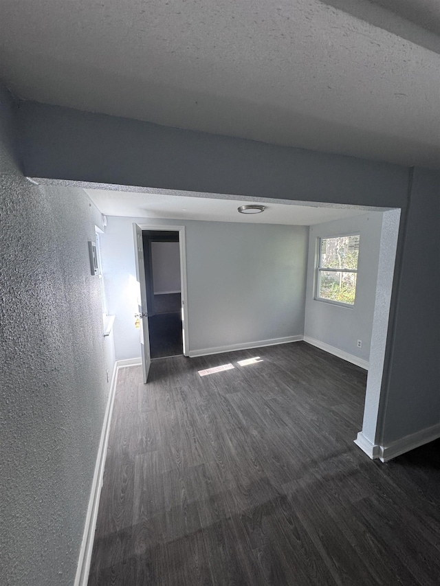 unfurnished room with dark hardwood / wood-style flooring and a textured ceiling