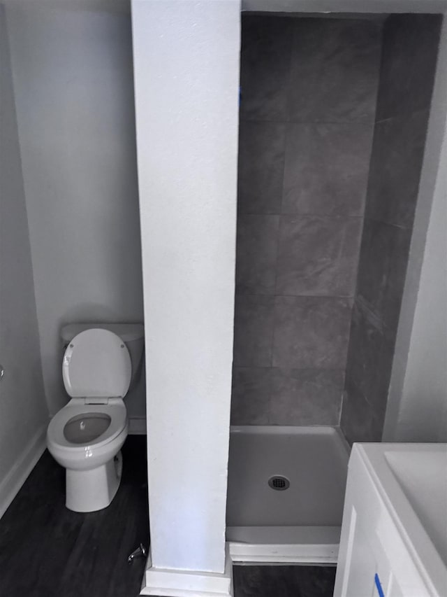 bathroom with a tile shower and toilet