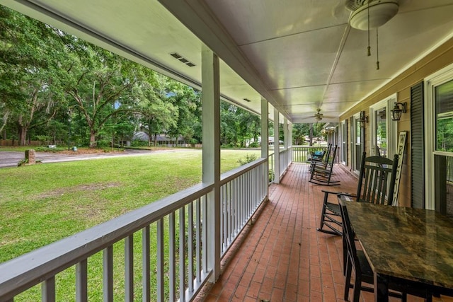 wooden deck with a yard, ceiling fan, and a porch