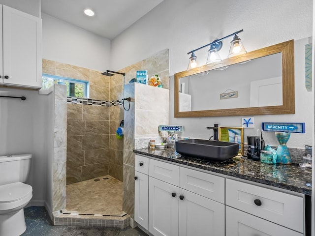 bathroom featuring a tile shower, vanity, and toilet