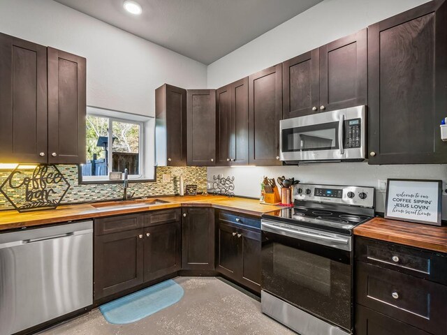 kitchen with dark brown cabinetry, sink, wood counters, tasteful backsplash, and appliances with stainless steel finishes