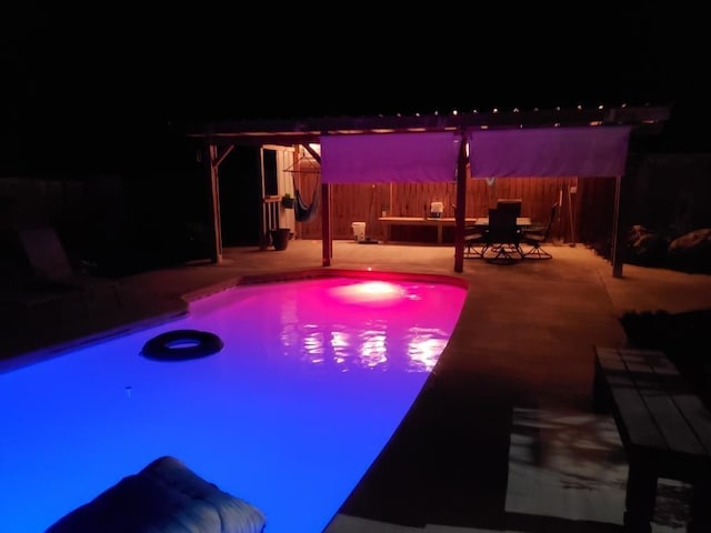 pool at night with a jacuzzi and a patio