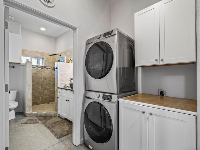 laundry area featuring cabinets and stacked washing maching and dryer