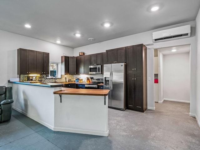 kitchen featuring wood counters, kitchen peninsula, appliances with stainless steel finishes, a wall mounted AC, and dark brown cabinetry