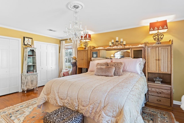 bedroom with crown molding, hardwood / wood-style flooring, and multiple closets