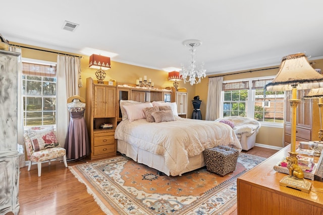 bedroom featuring wood-type flooring, a notable chandelier, and crown molding