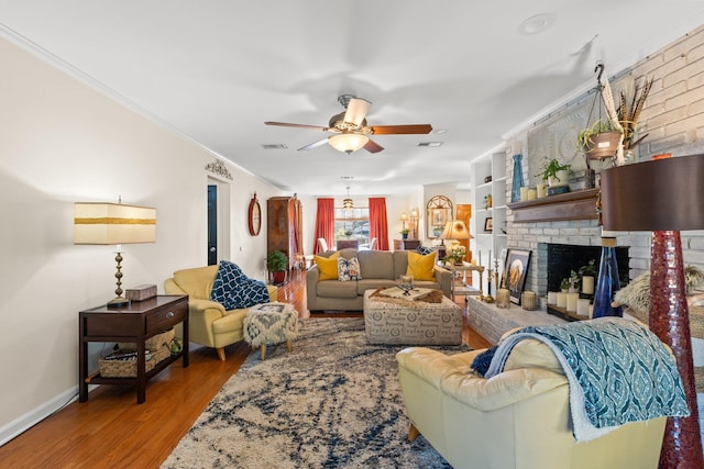 living room with crown molding, ceiling fan, hardwood / wood-style floors, and a brick fireplace