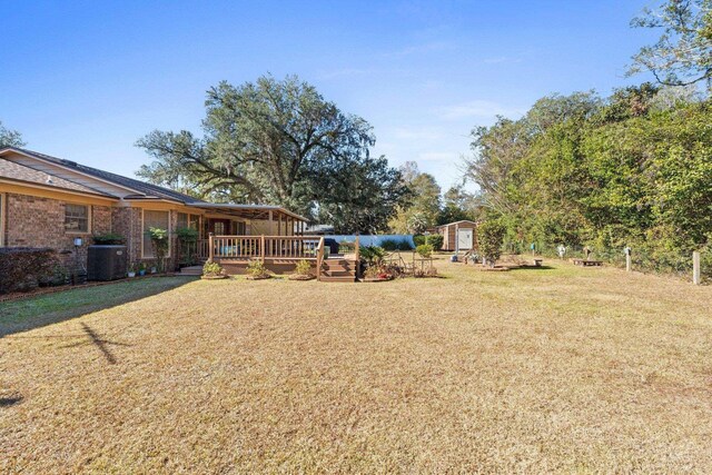 view of yard featuring central AC, a storage unit, and a deck