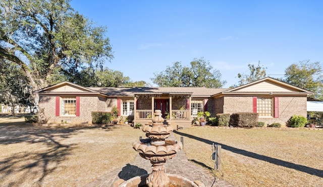 ranch-style house featuring covered porch and a front lawn