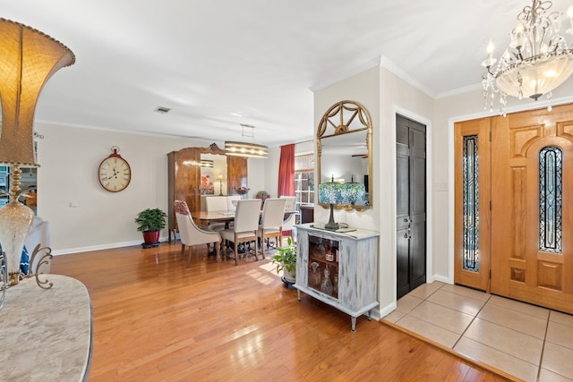 foyer entrance with crown molding, a chandelier, and light hardwood / wood-style flooring