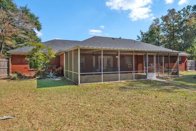 rear view of property featuring ceiling fan, a sunroom, and a lawn