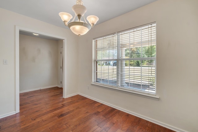 empty room featuring a notable chandelier and dark hardwood / wood-style floors