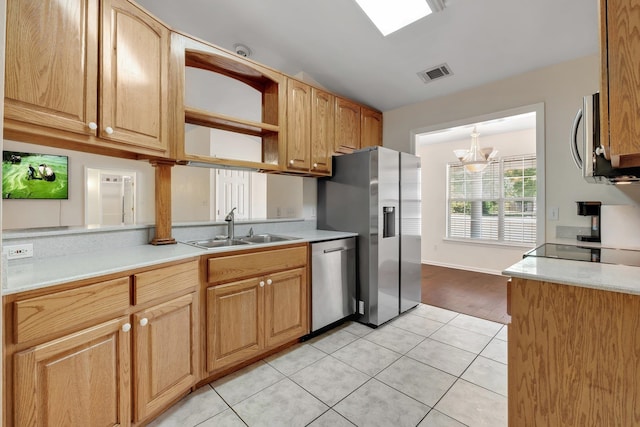 kitchen featuring an inviting chandelier, light tile patterned floors, sink, a skylight, and stainless steel appliances