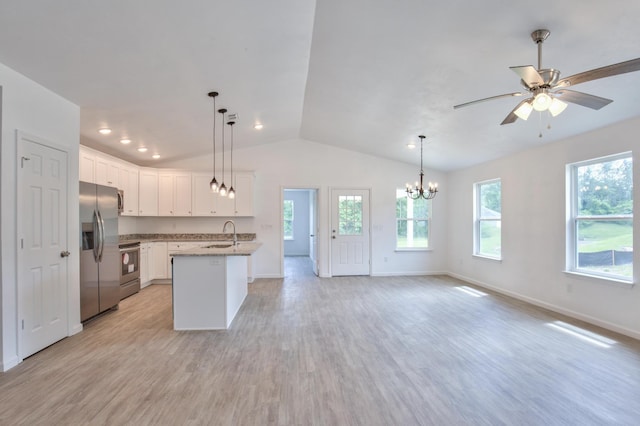 kitchen featuring vaulted ceiling, a sink, appliances with stainless steel finishes, open floor plan, and white cabinetry