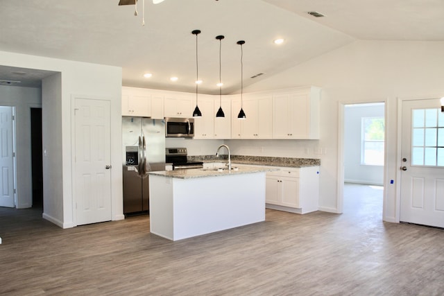 kitchen featuring stainless steel appliances, wood finished floors, a sink, and light stone counters