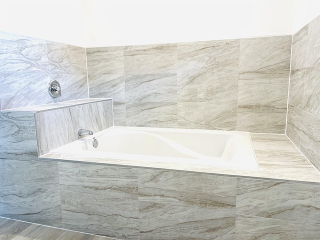 bathroom with a washtub and tiled shower