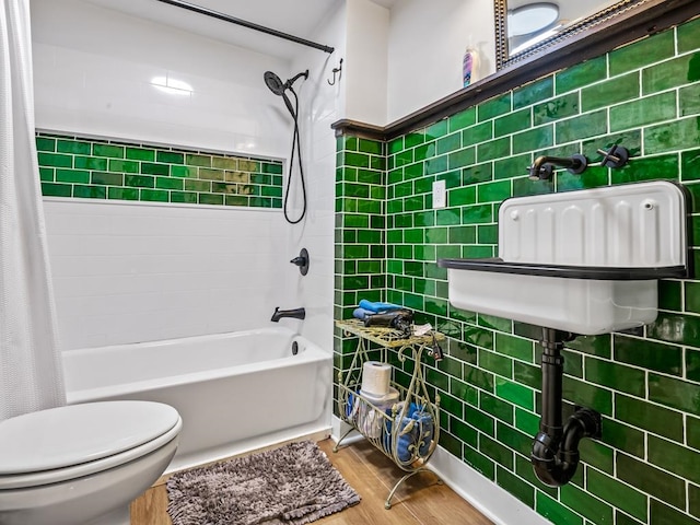 bathroom featuring wood-type flooring, toilet, tile walls, and shower / tub combo with curtain