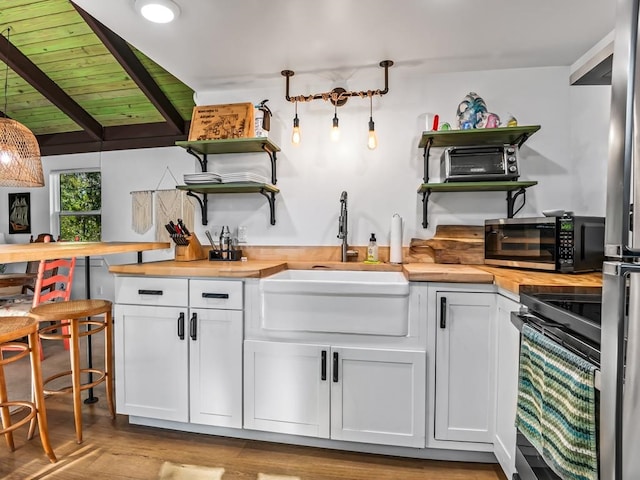 kitchen with white cabinetry, wooden ceiling, wood counters, vaulted ceiling with beams, and appliances with stainless steel finishes