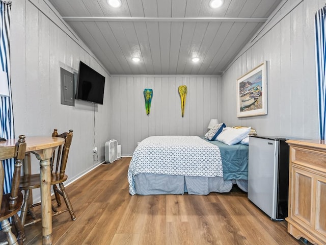 bedroom with stainless steel fridge, hardwood / wood-style flooring, wood ceiling, and wood walls