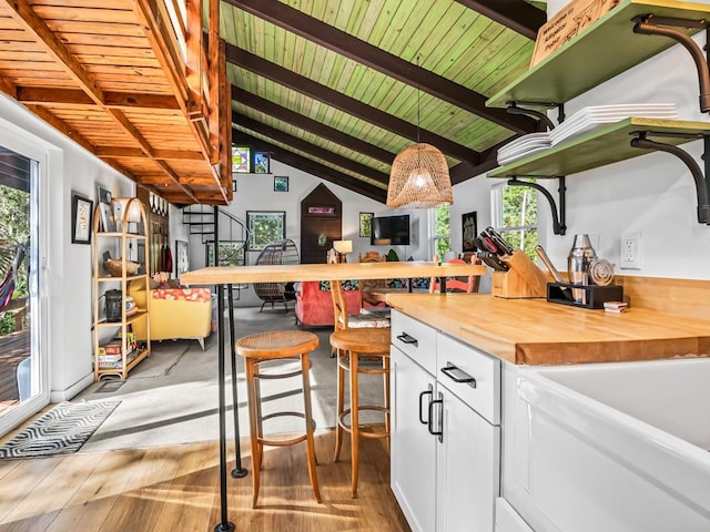 kitchen featuring white cabinets, a wealth of natural light, butcher block countertops, and hanging light fixtures