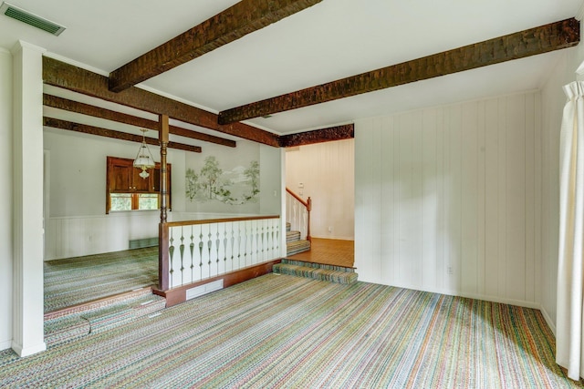 unfurnished room featuring beamed ceiling and carpet