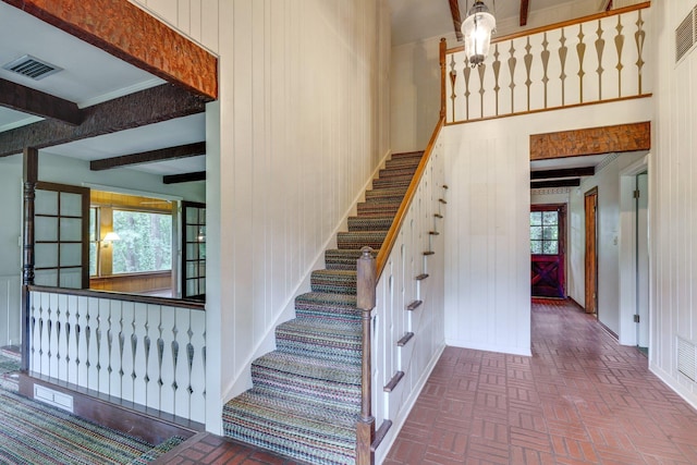 stairway featuring beamed ceiling