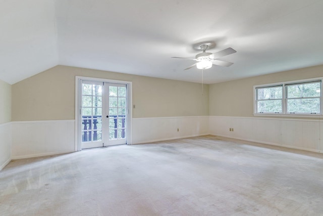 carpeted spare room with lofted ceiling, ceiling fan, and french doors