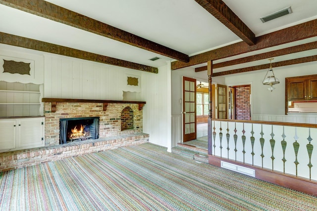 unfurnished living room featuring beam ceiling, a brick fireplace, and light carpet